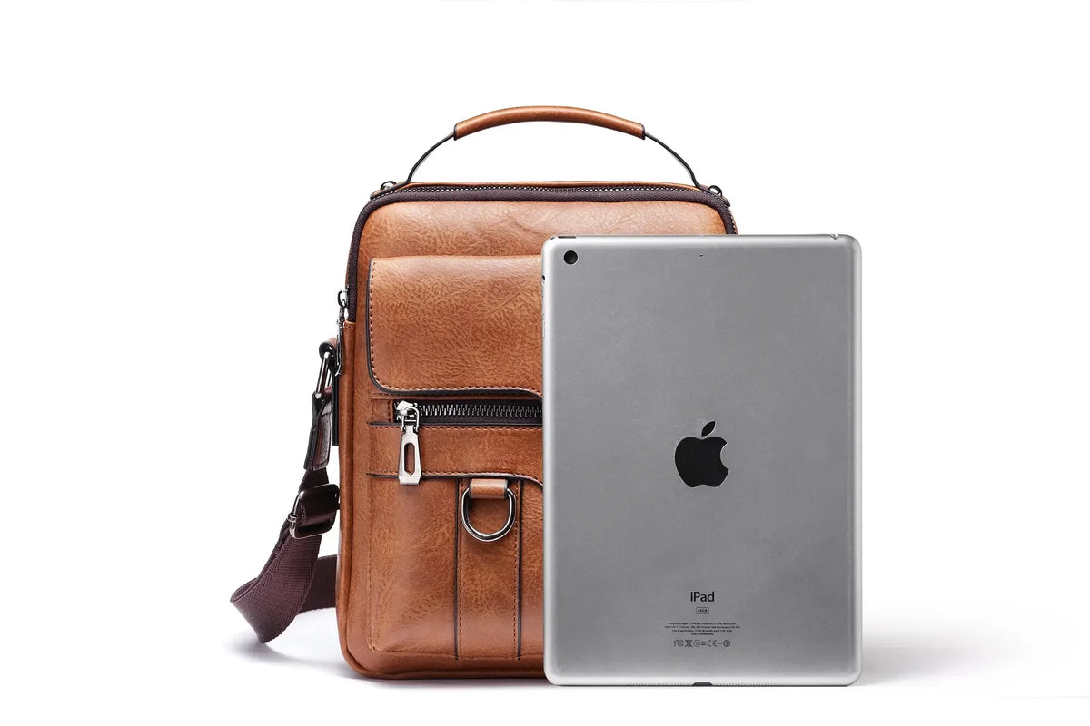 A brown vintage PU leather crossbody messenger bag with a leather strap and a silver iPad inside.