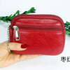 A hand holds a red PU leather mini wallet with a silver keychain against a white background.