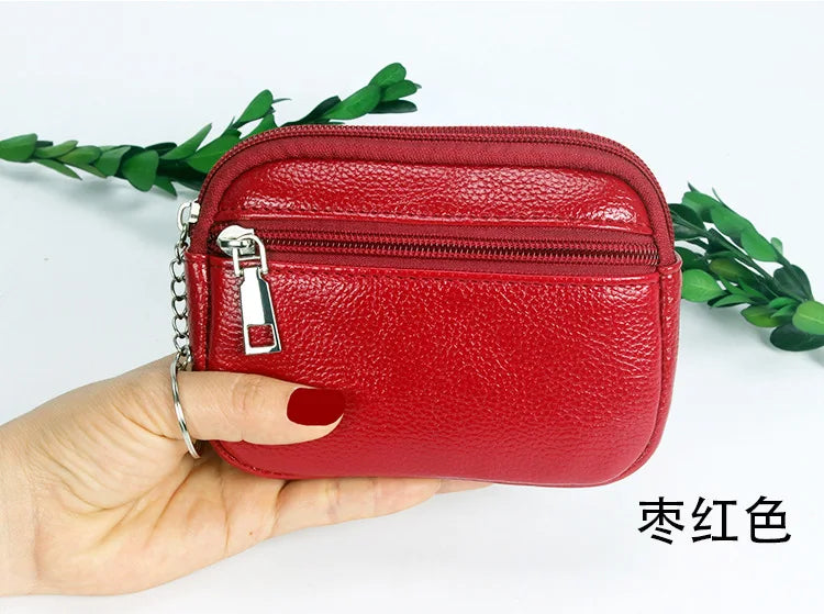 A hand holds a red PU leather mini wallet with a silver keychain against a white background.
