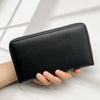 A black multi-card men's commuter wallet is held by a hand against a bright white background.