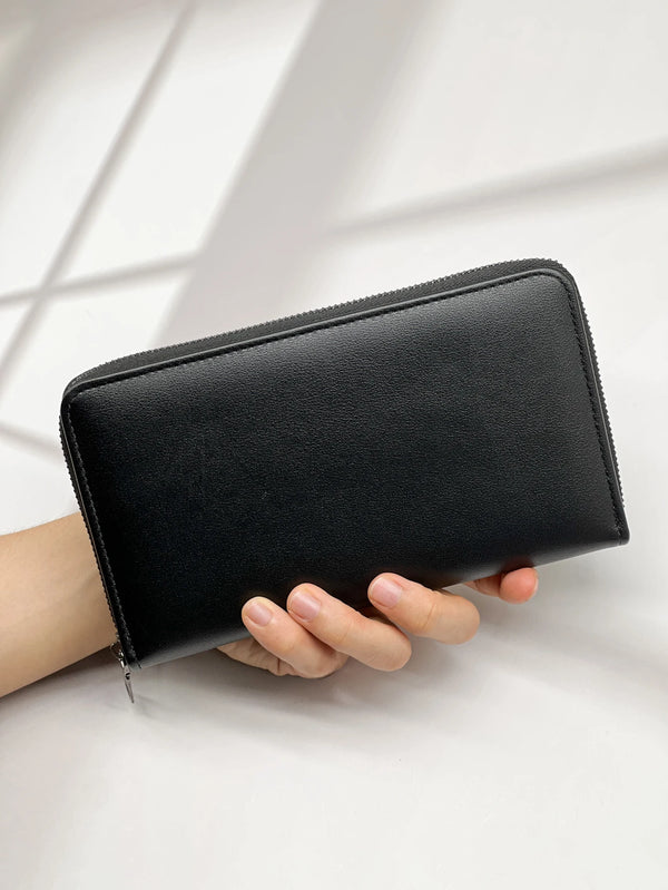 A black multi-card men's commuter wallet is held by a hand against a bright white background.