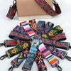 A beige clutch bag with a patterned strap and multiple colorful adjustable crossbody straps displayed on a white background.