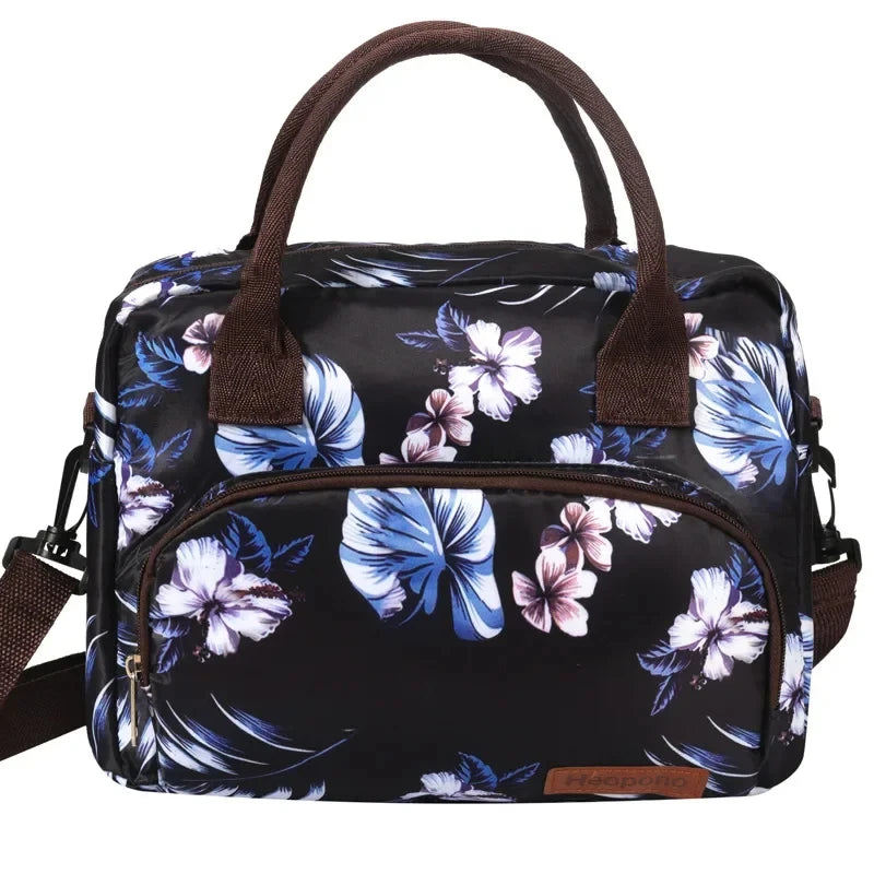 Bolsa térmica portátil con estampado floral blanco y negro y correas marrones.