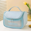 Sac de toilette transparent bleu clair et imperméable avec poignée, sur une surface blanche.