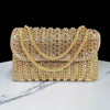 A rectangular gold and rose gold rhinestone evening clutch bag with a diamond chain resting on a white marble surface.