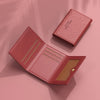 Cartera de cuero rosa de varias tarjetas abierta, mostrando una ranura y una cubierta texturizada.
