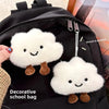 Black school bag featuring white cloud shaped plush keychains and brooch pins
