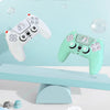 A light green silicone grip cover for a PlayStation controller featuring a cat design, displayed on a blue surface.