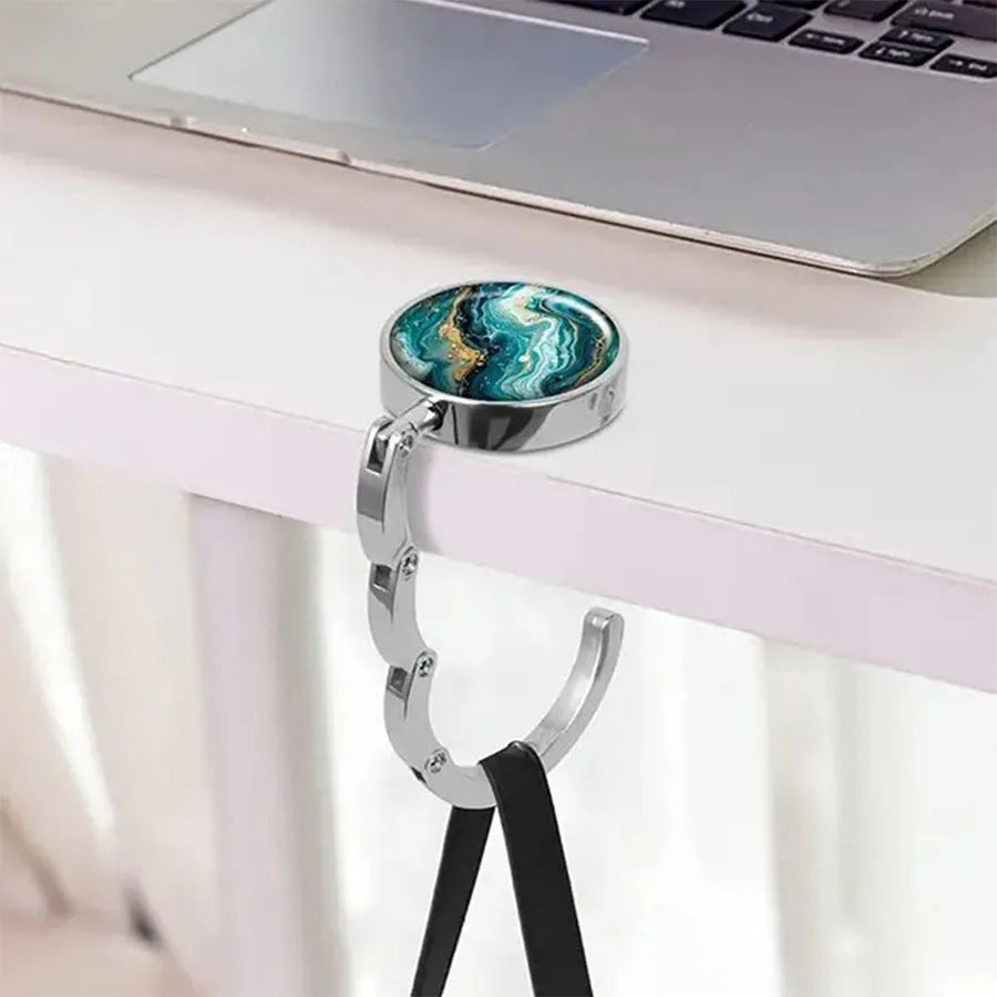 Silver pendant with a marbled blue and green stone attached to a black leather strap for a portable bag hook