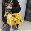 A woman holds a yellow and white nylon crossbody shoulder bag with black accents.