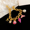Gold chain bracelet featuring an ocean pearl charm, starfish, and pink shell accents.