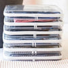 A stack of clear plastic storage pouches filled with folded clothing, stacked horizontally on a white surface.