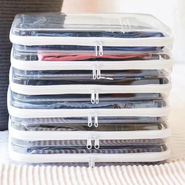 A stack of clear plastic storage pouches filled with folded clothing, stacked horizontally on a white surface.