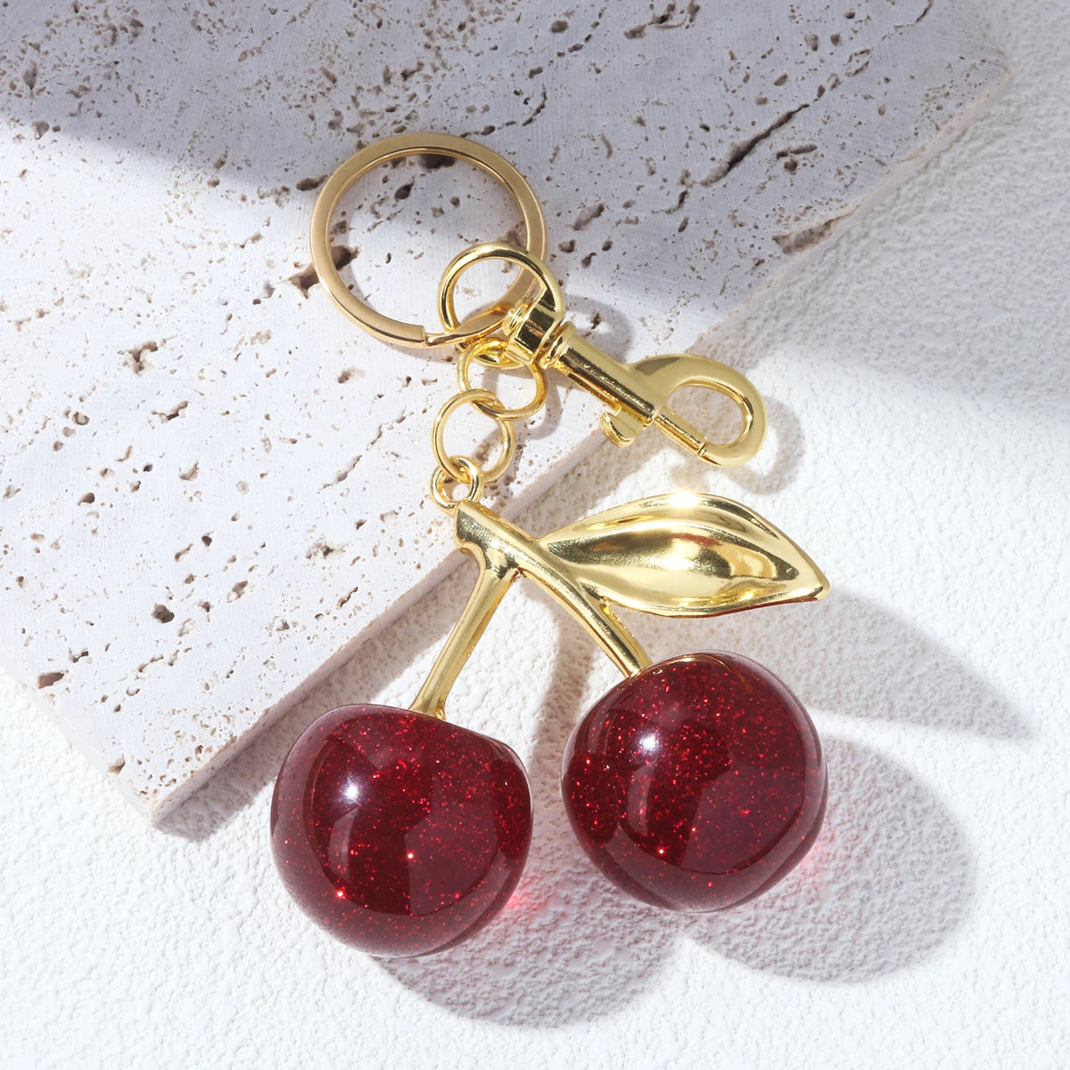 Gold-toned keychain featuring a shiny red crystal cherry fruit charm.
