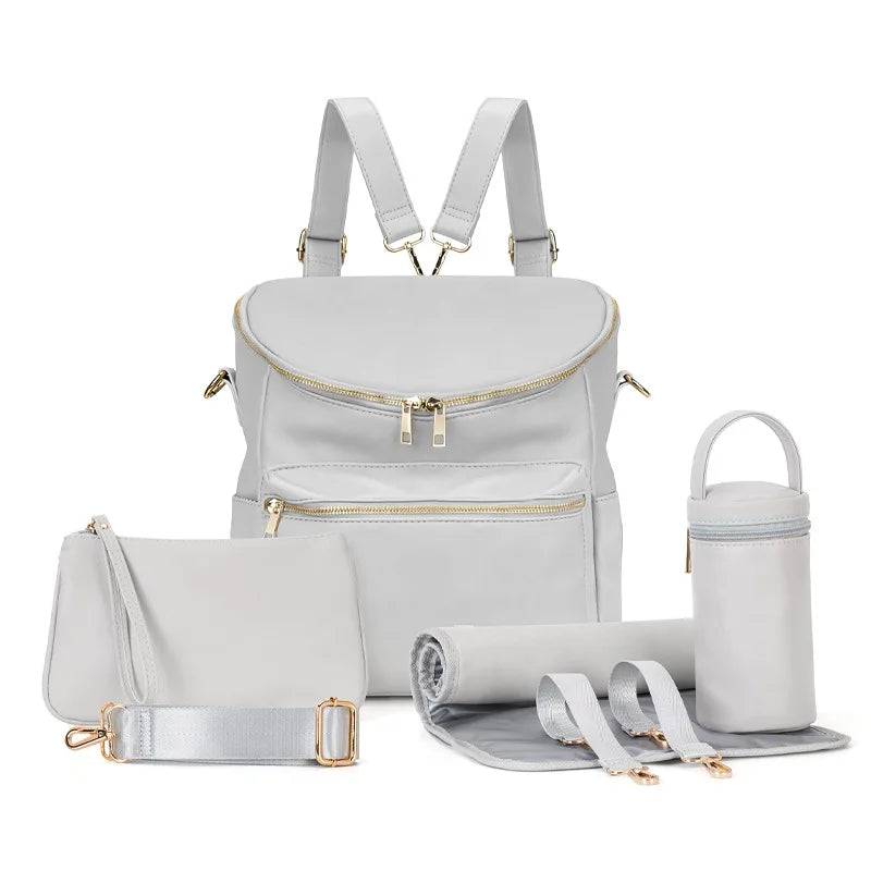 A light gray large capacity diaper bag backpack with gold zippers and a matching storage pouch.