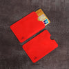Two red anti-scan card sleeves for credit and RFID protection placed on a dark surface.