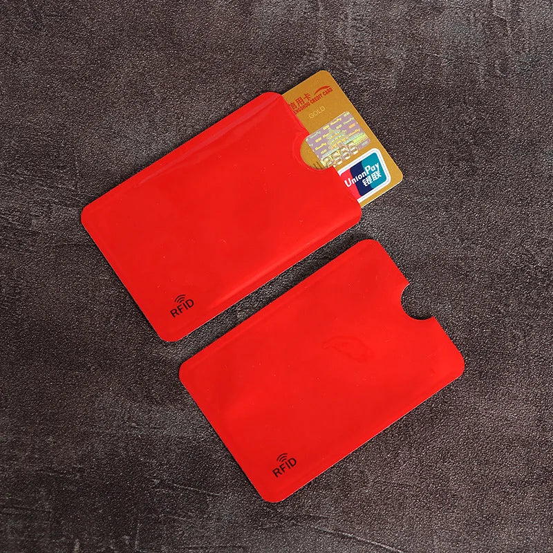 Two red anti-scan card sleeves for credit and RFID protection placed on a dark surface.