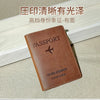 A brown genuine leather passport holder and travel wallet with a leather cover and an embossed airplane design.