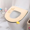 A beige plush waterproof toilet seat cover is shown placed inside a white toilet bowl.