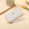 A light blue patterned zipper wallet lying on a beige surface next to a vintage-style clock and a yellow tulip.
