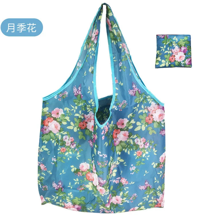A reusable eco tote shopping bag featuring a vibrant floral print of pink and blue flowers on a light blue background.