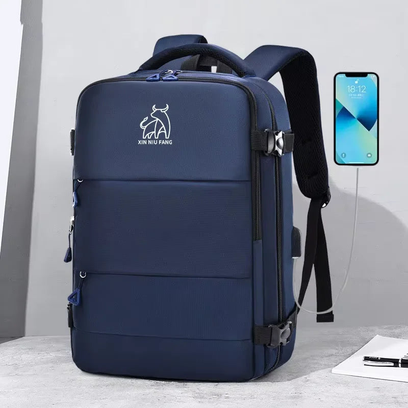 A navy blue expandable travel backpack with a black strap and a smartphone charging cable is displayed on a light surface.