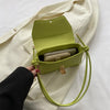 A lime green leather crossbody bag with a flap is shown open, resting on a cream-colored fabric.