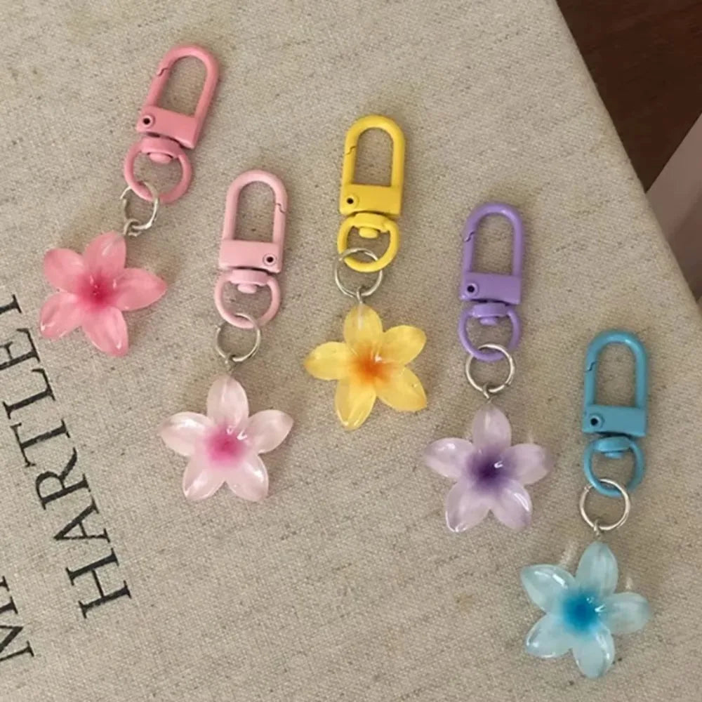 A collection of colorful resin flower keychains in pink, yellow, purple, and blue hanging from metal rings.