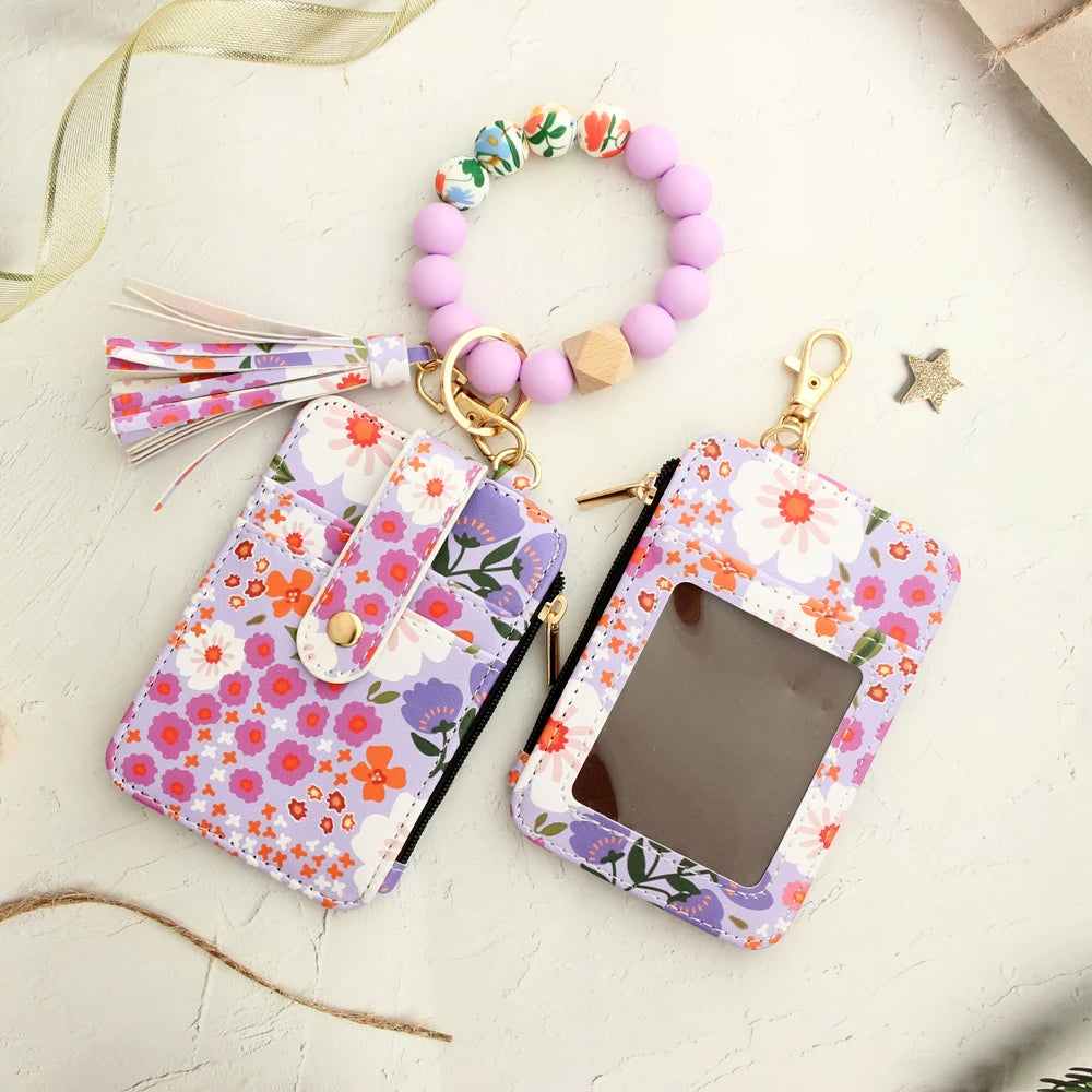 A purple and pink floral silicone bead key chain wallet with a clear window and a beaded bracelet