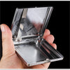 A hand holds open a decorative metal cigarette storage box showing intricate patterns on the lid and perforated bottom.
