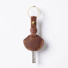 A brown genuine leather key fob cover with a metal keychain ring and key.