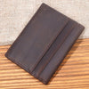A dark brown genuine leather bifold card holder resting on a wooden surface.