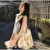A woman wearing a white top and dark skirt holds a bohemian floral patchwork shoulder bag outdoors.