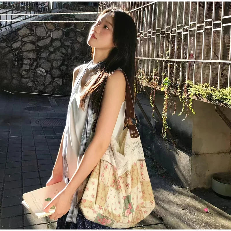 A woman wearing a white top and dark skirt holds a bohemian floral patchwork shoulder bag outdoors.