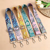 A collection of colorful bohemian printed crossbody straps with metal clasps arranged on a neutral background.
