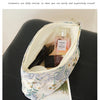 A light blue floral canvas makeup bag is open, showing a glass perfume bottle and other cosmetics inside.
