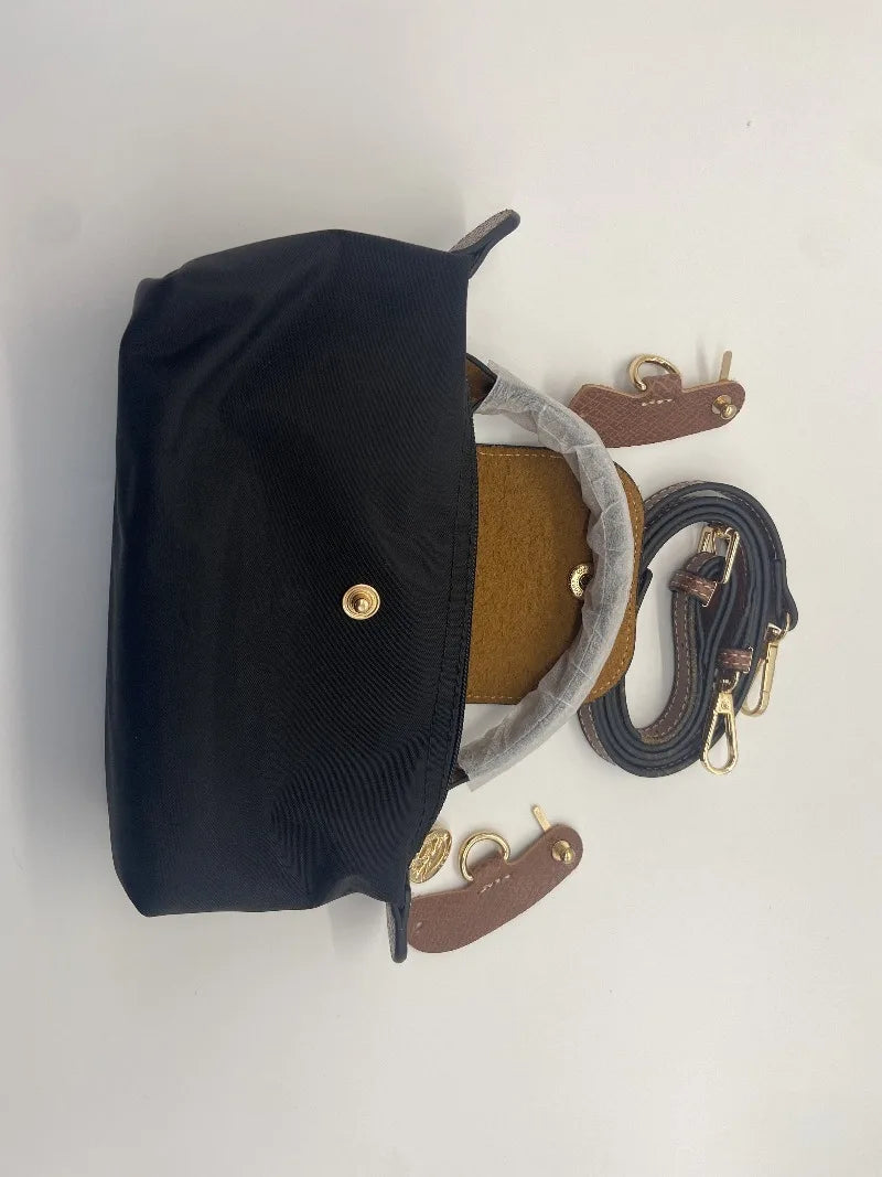 Black waterproof nylon crossbody bag with a tan leather pouch and gold hardware.