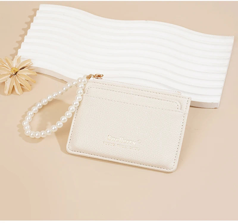 Beige Leder-Karteikartenetui mit Perlenkette neben einem weißen gewellten Kartenhalter