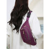 A purple nylon crossbody belt bag worn by a woman with long dark hair, shown from the back.