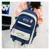 A navy blue nylon backpack set featuring cartoon designs and white accents, worn by a person.