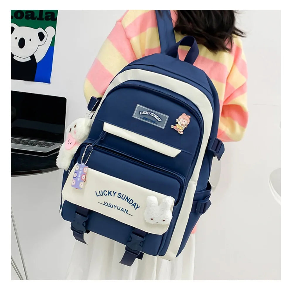 A navy blue nylon backpack set featuring cartoon designs and white accents, worn by a person.