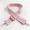 A pink woven handbag strap with an arrow jacquard pattern shown crossed on a white background.