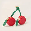A red cherry fruit shaped coin purse keychain with green leather accents and gold hardware.