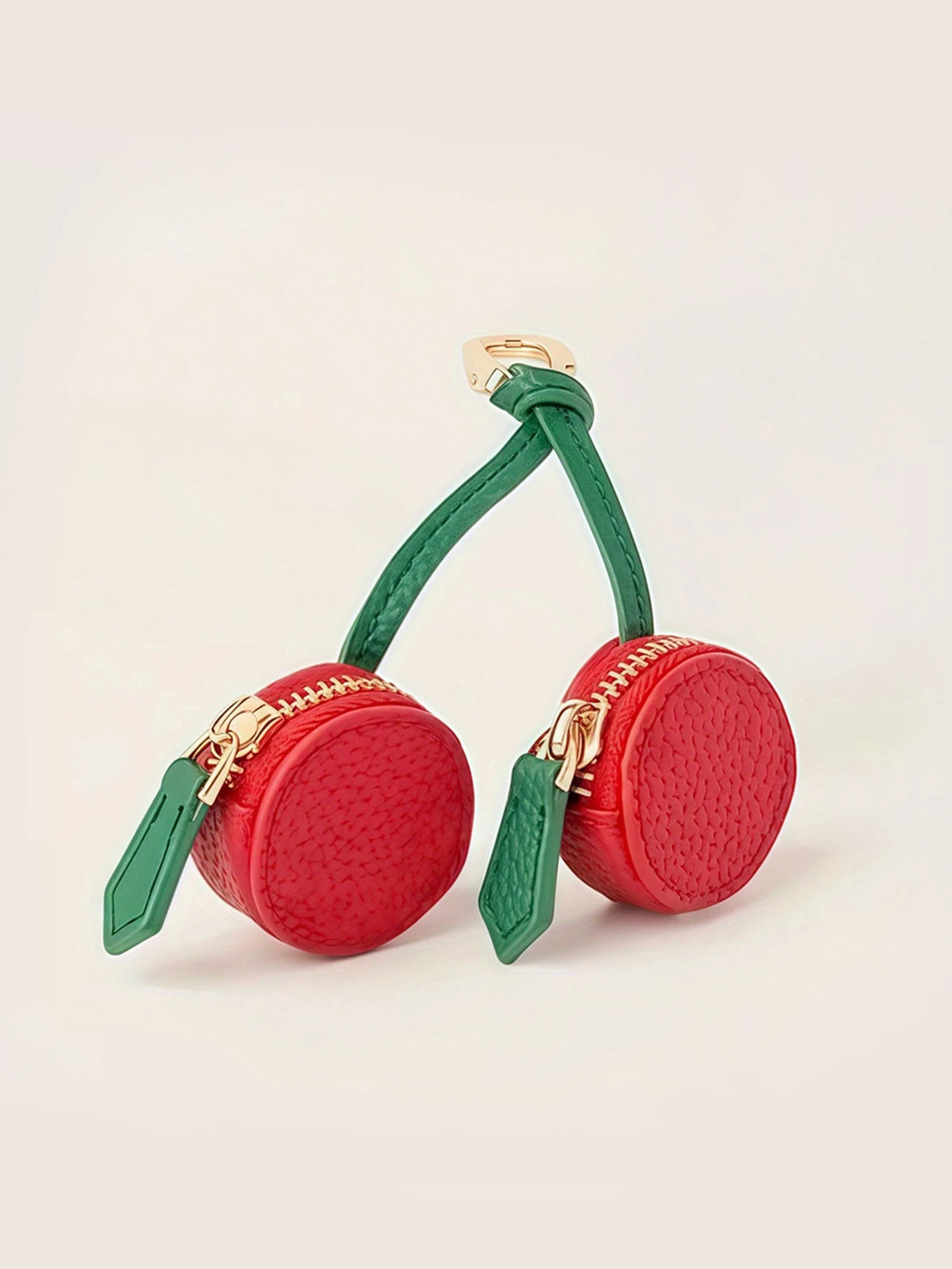 A red cherry fruit shaped coin purse keychain with green leather accents and gold hardware.