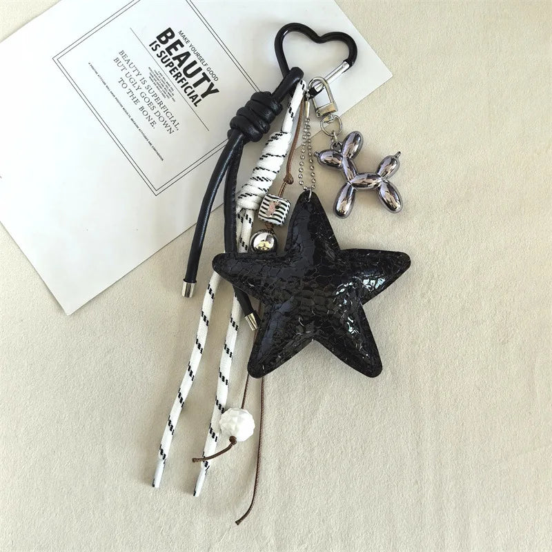 Charm étoile noire avec pendentif chien argenté et cordon en cuir rayé blanc sur fond clair.