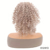 A light brown, curly hair extension is displayed on a mannequin head.