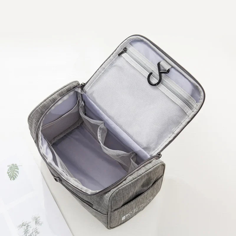 A gray portable Oxford cloth toiletry bag is shown open, displaying a padded interior and a mesh lining.