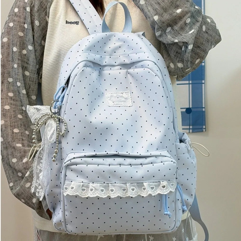 A light blue polka dot nylon travel backpack with a white lace trim and a laptop compartment worn by a person.
