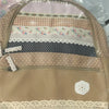 A vintage floral print backpack with layered fabric panels in pink, white, and beige tones.