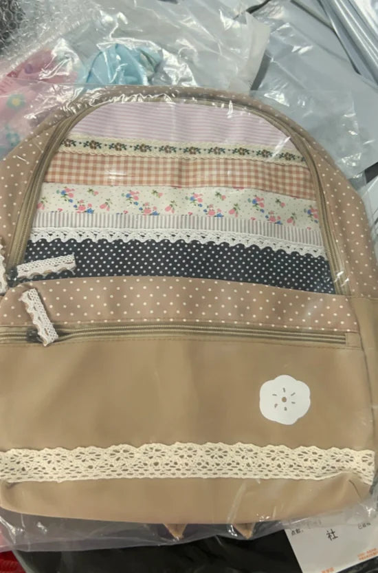 A vintage floral print backpack with layered fabric panels in pink, white, and beige tones.